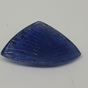 May include: A triangular blue gemstone with a carved leaf design.