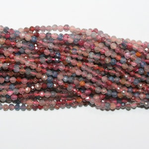 Peut inclure: Des rangées de perles de pierres précieuses facettées dans des tons de rose, de rouge et de bleu. Les perles sont petites et rondes, avec une finition polie et scintillante. Ces perles sont enfilées, prêtes pour la création de bijoux.