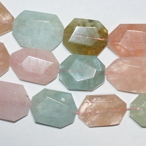 May include: A strand of faceted gemstone beads in shades of pink, green, and brown. The beads are all octagonal in shape and have a smooth, polished finish.
