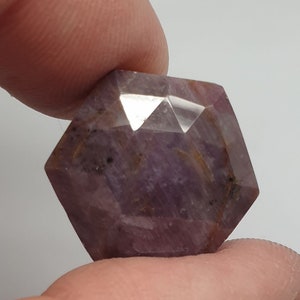 Op de afbeelding: Een gefacetteerde edelsteen in paars en bruin met een zeshoekige vorm.