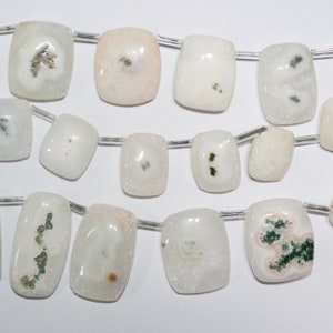 May include: A strand of white and pink agate beads with green inclusions. The beads are rectangular and have a rough, textured surface.