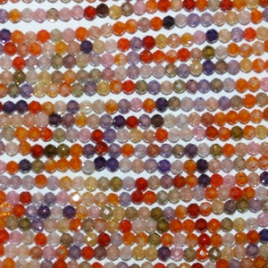 May include: Rows of faceted beads in a variety of colors, including orange, red, purple, pink, and green. The beads are small and round, and appear to be strung together. The background is white.