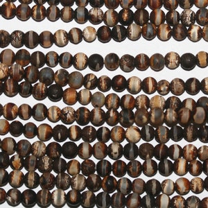 Può includere: Una collana di perle di agata marroni e bianche. Le perle sono rotonde e hanno una finitura naturale e lucida.