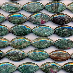 Pode incluir: Close-up de contas ovais em tons de verde, cinza e marrom. Cada conta apresenta uma faixa iridescente no topo, exibindo um espectro de cores. As contas parecem ser feitas de um material de pedra natural, dispostas em fileiras.