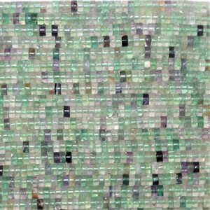 Könnte beinhalten: Eine Strähne aus quadratischen Perlen in Grün, Lila und Schwarz. Die Perlen sind aus Fluorit und haben eine Größe von etwa 6 mm.