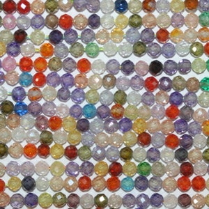 Op de afbeelding: Een close-up van een verzameling gefacetteerde edelsteen kralen in verschillende kleuren, waaronder rood, oranje, geel, groen, blauw, paars en helder. De kralen zijn aan elkaar geregen, waardoor een textuurrijke en kleurrijke weergave ontstaat.