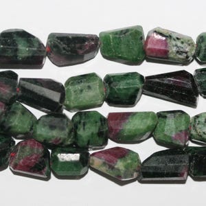 May include: A strand of green, black, and pink gemstone beads. The beads are faceted and have a rough, natural look.