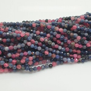 Op de afbeelding: Een streng facetgeslepen edelsteen kralen in tinten blauw en roze. De kralen zijn klein en rond en zijn geregen op een doorzichtige draad.
