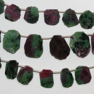 May include: Strands of raw ruby and zoisite gemstone beads. The beads are a mix of deep red and green colors, with a rough, irregular shape. The beads are strung on a thin, silver-colored wire, perfect for jewelry making.