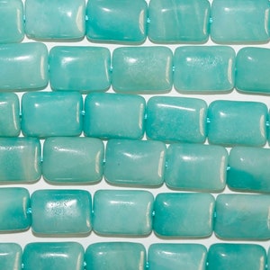 May include: A strand of smooth, rectangular beads in a vibrant turquoise blue colour. Each bead features a polished finish with subtle natural variations in tone and texture, arranged in horizontal rows and strung on a thin light blue thread.
