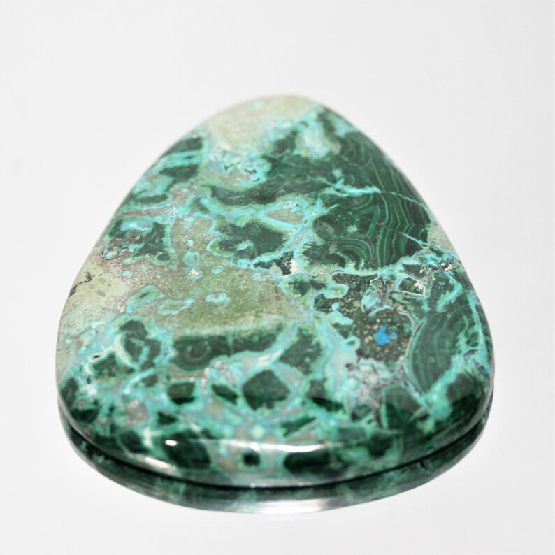 May include: A green and blue malachite cabochon with a smooth, polished surface. The stone has a unique pattern of swirls and veins.