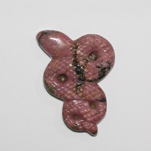 Può includere: Un ciondolo a forma di serpente intagliato in rodocrosite rosa e nera.