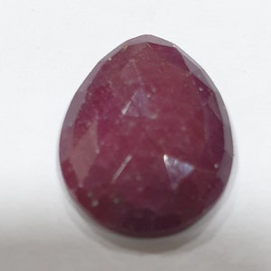 May include: A deep red gemstone with a faceted pear shape. The gemstone has a slightly cloudy appearance.
