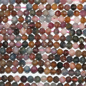 May include: A strand of faceted gemstone beads in various shades of pink, blue, and brown. The beads are strung on a pink thread.