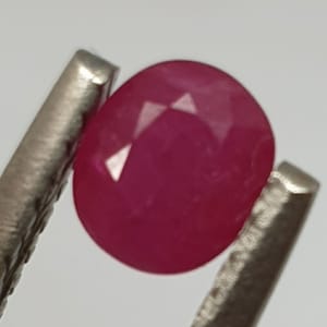 May include: A vibrant pink oval-shaped gemstone with a faceted cut.