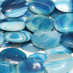 Può includere: Una collana di perline ovali in agata blu con motivi a spirale bianchi e blu. Le perline sono lisce e lucidate.