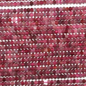 Op de afbeelding: Een streng roze en rode edelsteen kralen. De kralen zijn gefacetteerd en hebben een licht doorschijnende uitstraling.