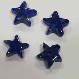May include: Four blue star-shaped lapis lazuli stones. The stones are smooth and polished, with a deep blue color and flecks of gold.
