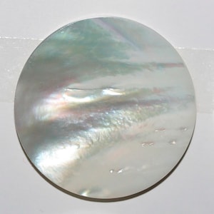 May include: A round, white, iridescent mother of pearl button with a smooth, polished surface.