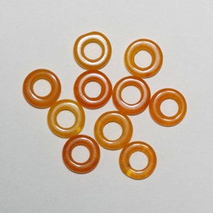 May include: Ten orange gemstone donut beads with a smooth, polished finish. The beads are all the same size and shape, and they have a hole in the center for stringing.