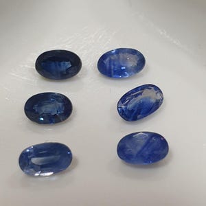 May include: Six oval-shaped blue sapphires, each with a different pattern of inclusions.