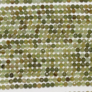 Pode incluir: Um fio de contas de pedra preciosa verde facetadas. As contas são redondas e têm uma forma ligeiramente irregular. São de cor verde claro com um ligeiro tom amarelo.