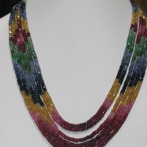 Peut inclure: Un collier à plusieurs rangs avec un dégradé de pierres précieuses colorées. Le collier présente un spectre de couleurs, dont le jaune, le rose, le vert, le bleu et le rouge foncé. Les pierres précieuses sont petites et facettées, créant un effet scintillant.