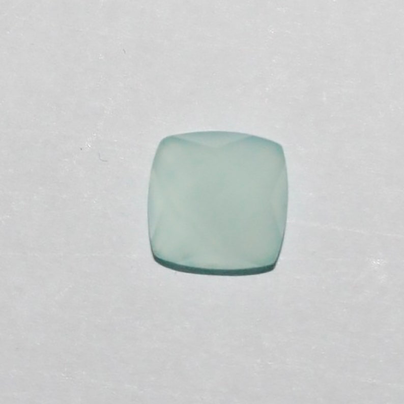 May include: A light blue, square-shaped gemstone with a faceted cut.