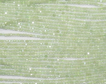 May include: Close-up of strands of light green, faceted beads. The beads are small and square-shaped, strung together in parallel lines. The beads have a subtle sparkle, and the overall effect is delicate and shimmering. Ideal for jewelry making.