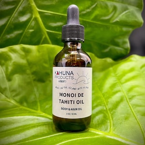 May include: A clear glass bottle with a black dropper top and a white label. The label says "Kahuna Products Hawaii" and "Monoi de Tahiti Oil Body & Hair Oil 2 oz / 60 ml".