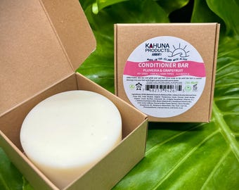May include: A white conditioner bar in a brown cardboard box. The box has a label that says "Kahuna Products Hawaii" and "Conditioner Bar Plumeria & Grapefruit".