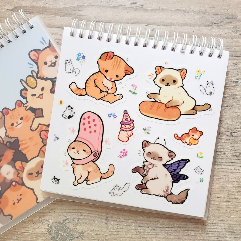 Puede incluir: Una ilustraci&oacute;n colorida de gatos con diferentes expresiones y accesorios. Los gatos est&aacute;n dibujados en un estilo de dibujos animados con colores brillantes y l&iacute;neas simples. La ilustraci&oacute;n incluye un gato con un sombrero, un gato con una baguette y un gato con alas.