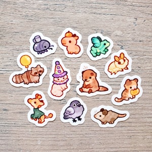 May include: A set of 11 colorful animal stickers featuring a raccoon, otter, cat, bird, frog, and more. The stickers are perfect for adding a touch of whimsy to journals, laptops, water bottles, and other surfaces.