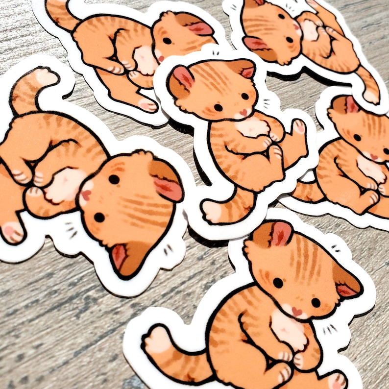 May include: A set of six orange and white cartoon cat stickers. Each sticker features a different pose of a cat with a white belly and orange stripes.