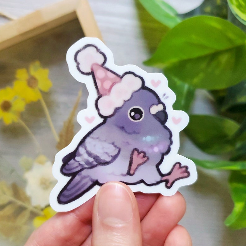 May include: A purple and white cartoon bird wearing a pink and white party hat with pink hearts around it.