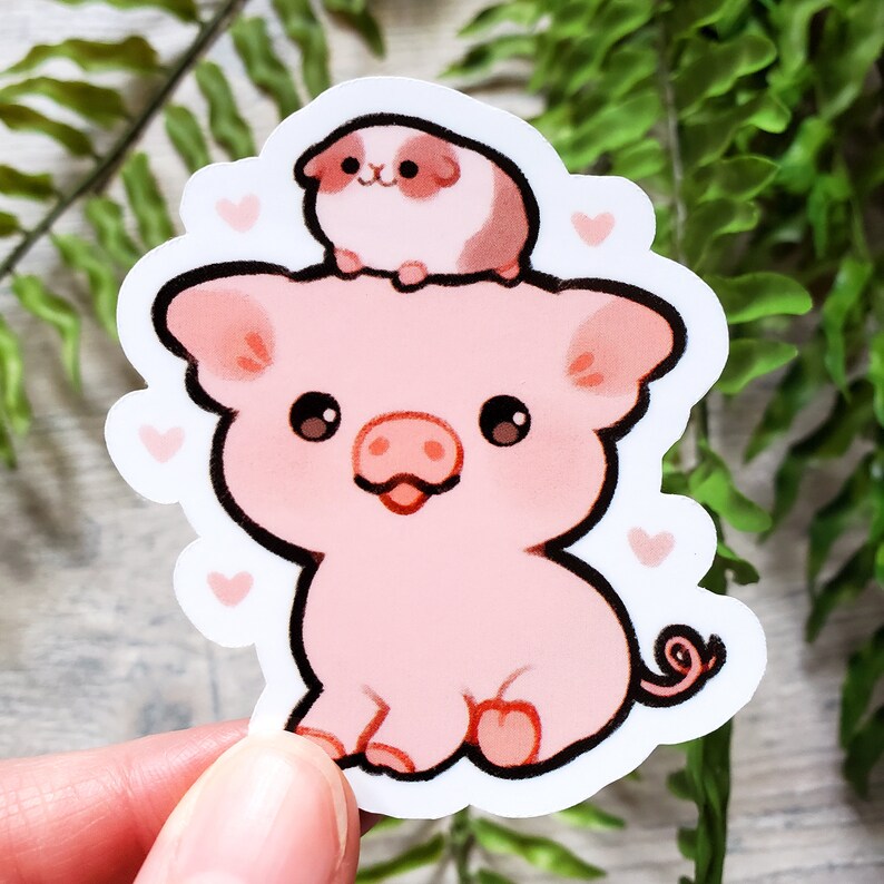 K&ouml;nnte beinhalten: Ein rosa Schwein-Aufkleber mit einem kleinen braunen und wei&szlig;en Meerschweinchen darauf. Das Schwein hat eine rosa Nase und eine rosa Zunge, die herausstreckt. Der Aufkleber hat einen wei&szlig;en Hintergrund mit rosa Herzen um das Schwein herum.