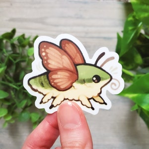 May include: A sticker of a cartoon moth with green and brown wings. The moth has a fuzzy body and large, round eyes.