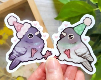 May include: Two cartoon pigeons wearing party hats. The pigeon on the left is purple and the pigeon on the right is white with pink accents. Both pigeons have large eyes and are holding their wings out.
