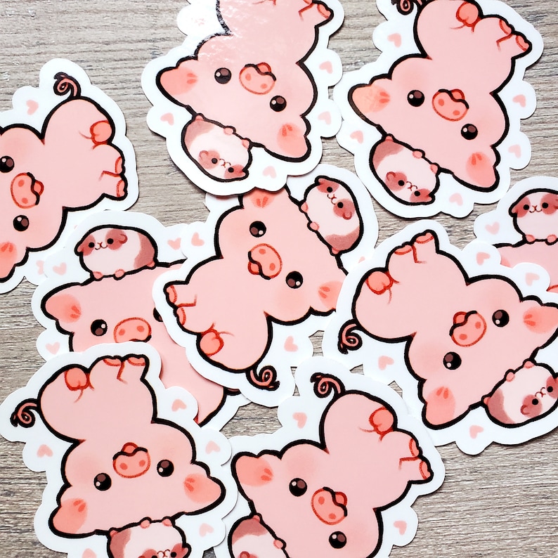 K&ouml;nnte beinhalten: Ein Set mit zehn rosa Schweinestickern, auf denen jeweils ein kleineres Schwein auf einem gr&ouml;&szlig;eren Schwein sitzt. Die Sticker befinden sich auf einer hellbraunen Holzoberfl&auml;che.
