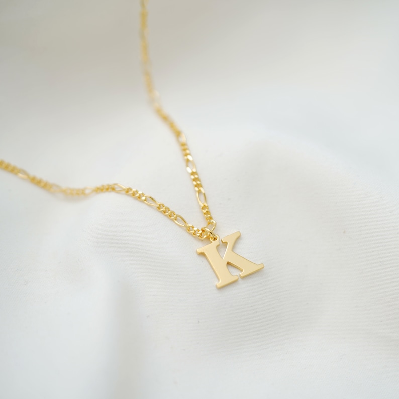 May include: A gold chain necklace with a gold letter K pendant.