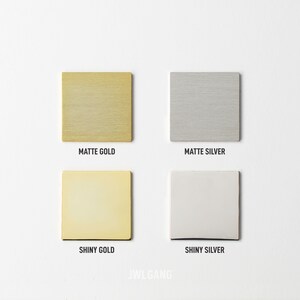 May include: Four metal squares, two gold and two silver, showing the different finishes available: matte gold, shiny gold, matte silver, and shiny silver.