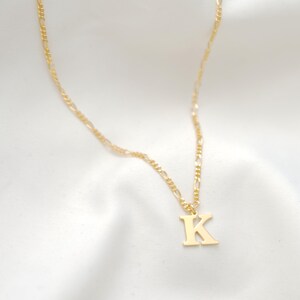 May include: A gold chain necklace with a gold letter K pendant.