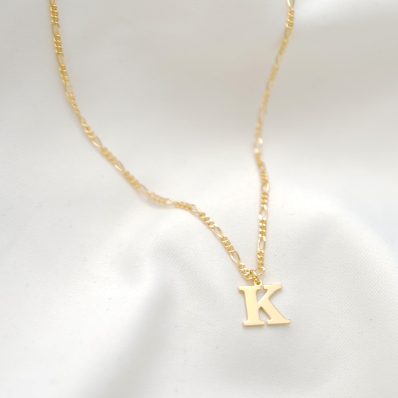 May include: A gold chain necklace with a gold letter K pendant.