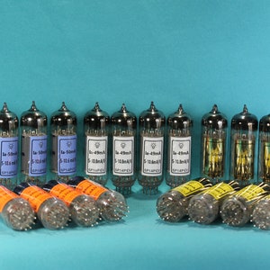 May include: A collection of 14 silver vacuum tubes with black and white labels. The labels have text that reads "La-50mA 5-10.6mA/V" and "La-49mA 5-12.8mA/V".