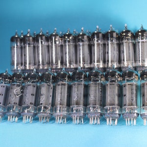 May include: A group of 20 silver vacuum tubes, arranged in two rows, on a light blue surface. The tubes are all the same size and shape, and they have a clear glass body with a silver metal top.