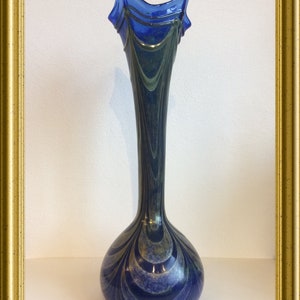 Peut inclure: Un vase en verre bleu et vert avec un motif tourbillonnant. Le vase a une large ouverture et un col étroit.