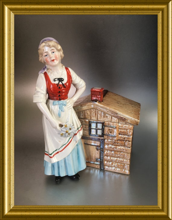 Antique German porcelain lidded figural tobacco jar: woman standing before a little house