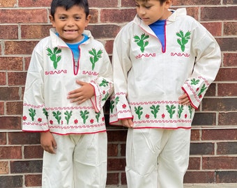 May include: Two children wearing white shirts and trousers with green cactus embroidery. The shirts have red trim and the trousers have red and green trim. The shirts also have the word "BABABAS" embroidered on them.