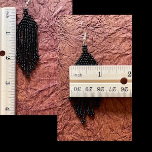 May include: Black beaded fringe earrings measuring approximately 2 inches in length. The earrings are shown next to a ruler for size reference.