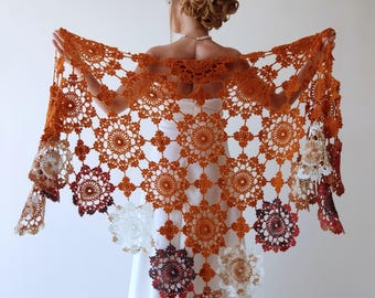 May include: A crocheted shawl with a large, intricate design in shades of orange, red, and white. The shawl is made of delicate, openwork stitches and has a scalloped edge.